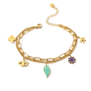 Close-up of golden double-layer steel bracelet featuring enamel charms and paperclip chain