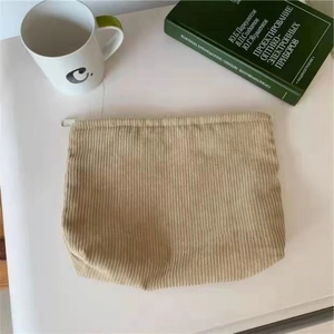 Close-up of beige corduroy pouch with zipper on a desk with a mug and book