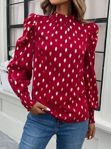 Detail of red crew neck blouse with gold polka dots and smocked cuffs on sleeves