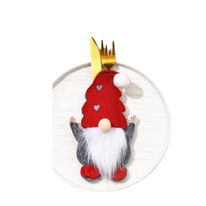 Christmas gnome cutlery holder with red hat and gold utensils on a white plate