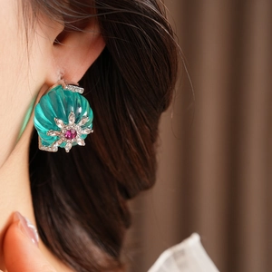 Close-up of vintage flower earrings featuring green shell resin and sparkling crystals
