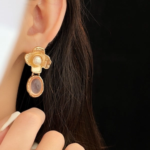 Detail of vintage flower earrings with pearls and purple stones worn by a model