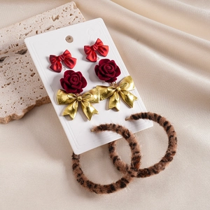 Dettaglio del set orecchini con rosa in velluto rosso e cerchi leopardati su seta beige