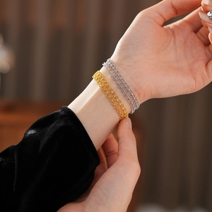 Close-up of gold and silver woven beaded bracelets on wrist with detailed metal texture