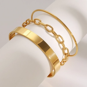 Nahaufnahme von drei goldenen Edelstahlarmbändern auf einem weißen Zylinder-Displayständer