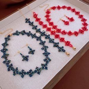 Détail de l'ensemble collier et boucles d'oreilles en perles sur plateau en lin beige