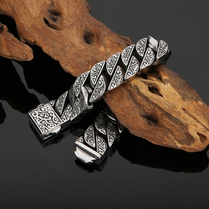 Macro shot of silver vintage titanium steel bracelet with engraved patterns on dark wood