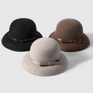 Close-up of wool felt cloche hats in black, brown, and grey with elegant silk bows