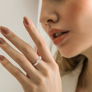 Nahaufnahme eines S925 Silberperlenrings mit zentralem Stein an einem Finger des Modells