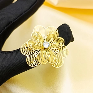 Close-up of gold hollow floral ring with white zircon center on a luxury satin background