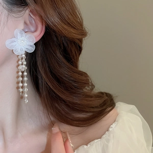 Detailed view of elegant white lace flower earrings with pearl tassels on model