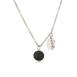 Detailed macro view of silver chain necklace with matte black bead and polished round tag