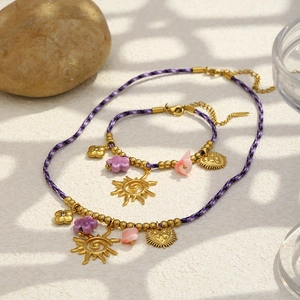 Détail d'un ensemble de bijoux en corde tissée avec pendentifs dorés et perles colorées
