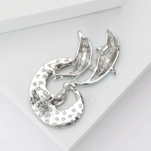 Macro view of a silver dolphin brooch featuring star textures and secure safety pin back
