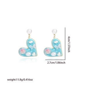 Detailed view of heart-shaped pearl earrings with size dimensions and blue oil painting style