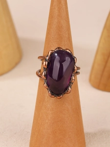 Vintage bronze ring with raw purple amethyst crystal on a wooden display stand