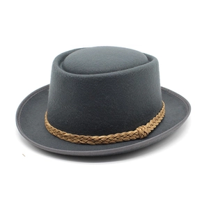 Detail of dark grey wool pork pie hat with a brown woven decorative band on white background