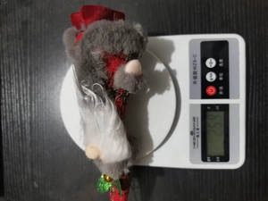 Detailed view of plush Christmas gnome ornament on scale showing 25.9g weight