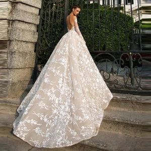 Lace bridal gown with long sleeves, open back and long train in an outdoor setting