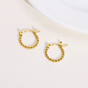 Detailed view of gold twisted hoop earrings with woven texture on minimalist background