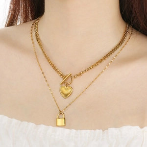 Detail of gold double-layered necklace featuring heart pendant and toggle clasp