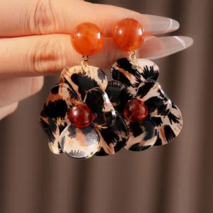 Retro leopard print resin flower earrings with orange beads held by hand