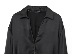 Dettaglio ravvicinato dell'elegante scollatura e del bottone di una camicia di raso nero
