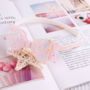 Détail d'un serre-tête rose avec nœud pailleté et sequins étoilés colorés sur un magazine