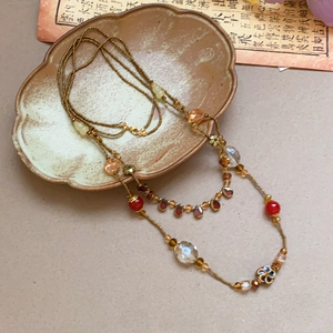 Detailed close-up of retro floral ceramic bead and crystal pendant on gold chain