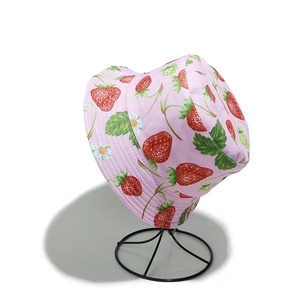 Detail of pink cotton bucket hat with strawberry print on black metal display stand