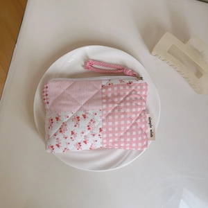Detail of pink floral quilted pouch with zipper, hand strap and patchwork texture