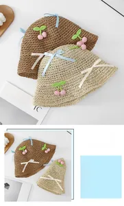 Detail of foldable woven straw hats with cherry crochet decor and ribbon bows