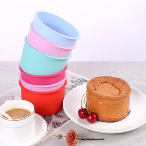 Set of five colorful round silicone cake molds stacked on a modern marble tabletop