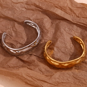 Macro shot of gold and silver plated open bangles with hammered texture on brown paper