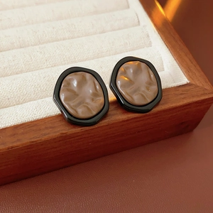 Macro detail of vintage irregular brown resin earrings on a beige velvet jewelry box