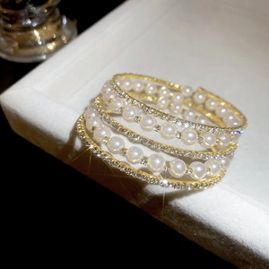 Detailed macro view of gold-tone pearl and rhinestone multi-layer wrap bracelet