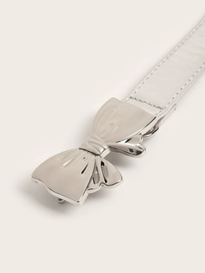 Detailed view of shiny silver bow buckle on metallic leather belt with fine stitching