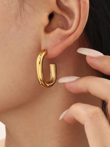 Close-up of gold double-layer C-shaped hoop earrings on model with polished metal finish