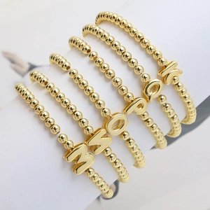 Detail of 18k gold-plated beaded elastic bracelets with various alphabet charms