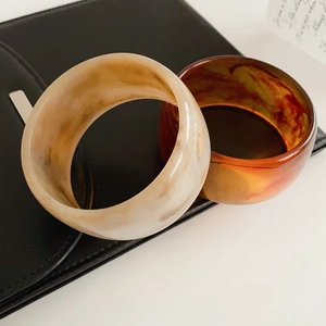 Close-up of vintage resin bangles in cream marble and amber brown textures