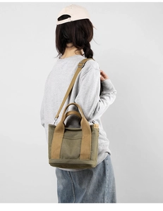 Detail of olive green canvas tote bag with adjustable brown shoulder strap on model
