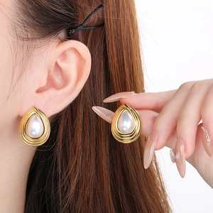 Detail of French style gold teardrop pearl earrings with wave pattern on model