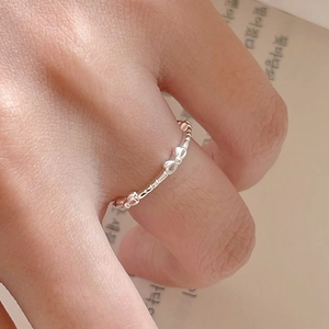Detailed close-up of a 925 silver bow ring with textured band on a finger