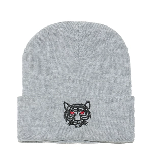 Close-up of gray knit beanie featuring detailed black tiger head embroidery with red eyes