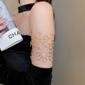 Detailed view of the hollow metal flower arm cuff on a model wearing an elegant dress