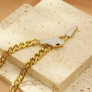 Chunky 18K gold snake head necklace with crystal pavé on a travertine stone
