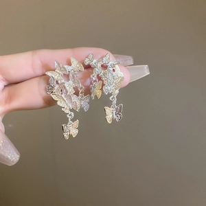Dettaglio degli orecchini a farfalla d'argento con design a strati e pendente