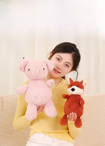 Close-up of a soft pink plush pig and brown fox toys held by a person in a cozy home