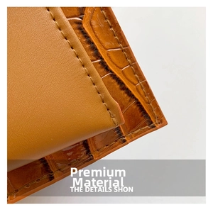 Detail of brown leather handbag featuring smooth texture and crocodile embossed stitching