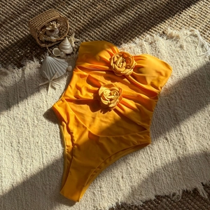 Detail of yellow one-piece swimsuit featuring 3D fabric roses and ruched texture